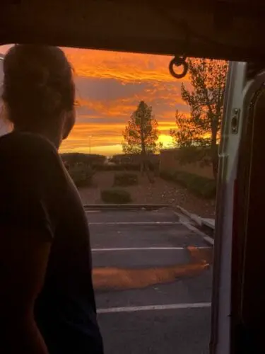 Woman Standing On Van Door Watching Sunset